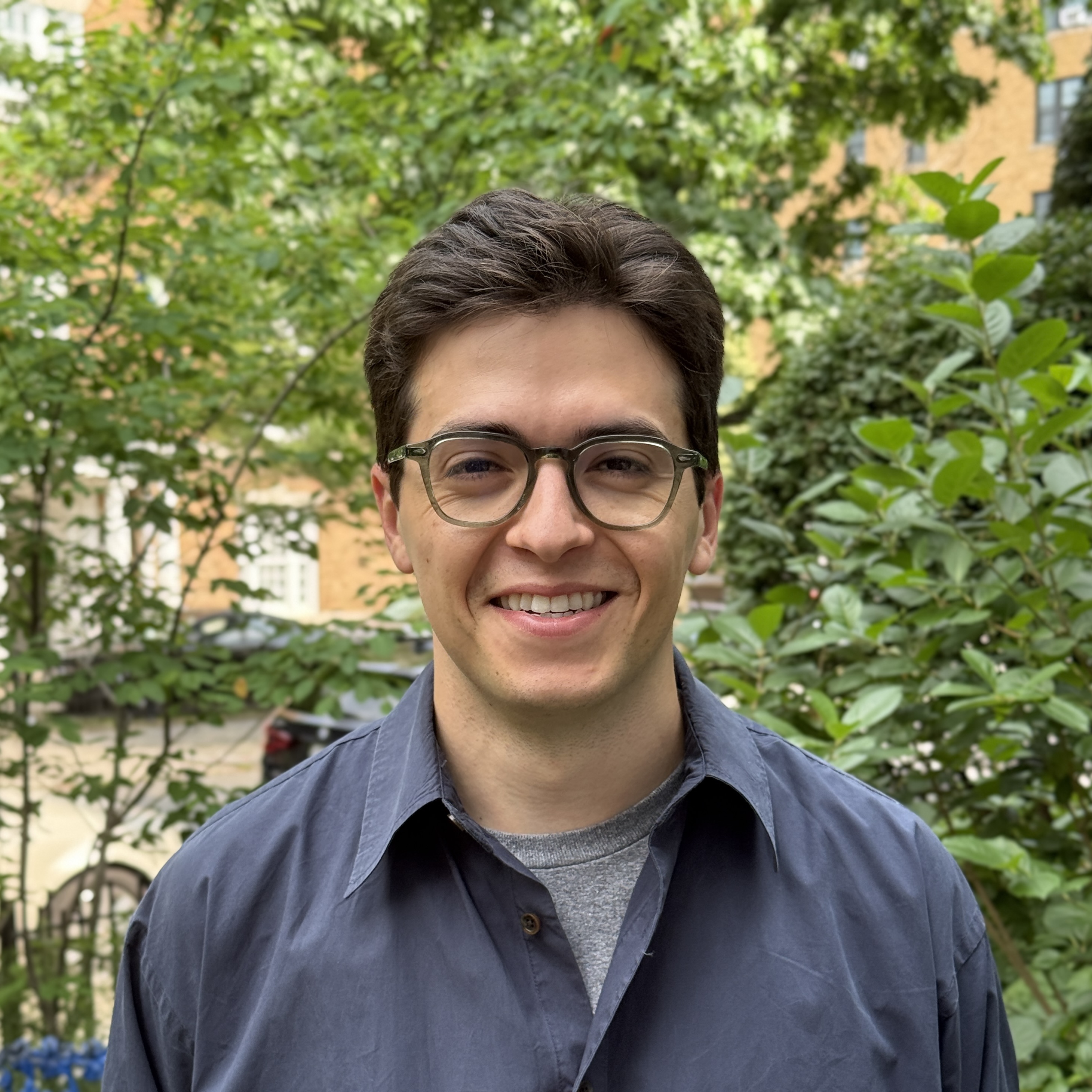 Andrew DeFrank, ANC 2B01 Commissioner, professional headshot showing him smiling outdoors with leafy background